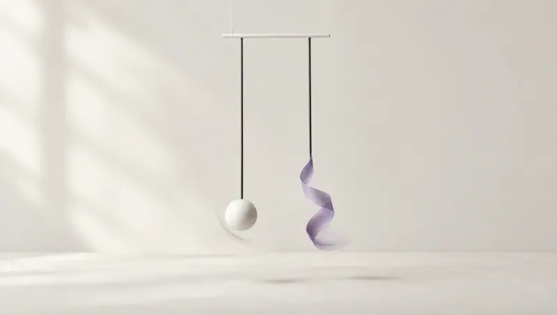Two slim pendulums swing from a white bar, one ending in a white sphere and the other in a curling lavender ribbon.