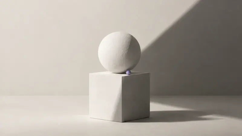 A white sphere on a white cube, cut by a clean diagonal shadow into a bright half and a dark half, with a tiny lavender bead on the edge between them.